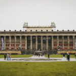 ddr museum berlin - Front view of the Altes Museum in Berlin with people and green lawn.