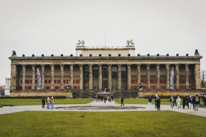ddr museum berlin - Front view of the Altes Museum in Berlin with people and green lawn.